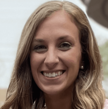 A woman with long, wavy blonde hair smiles at the camera. She has light skin and is wearing a light-colored top. The softly blurred background suggests a warm, welcoming setting—ideal for autism therapy near Chester County PA.