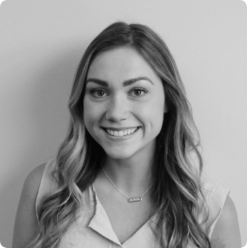 Black and white portrait of a young woman with long, wavy hair, smiling at the camera. She is wearing a sleeveless top and necklace, standing in front of a plain background—ideal for promoting autism services near Montgomery County PA.